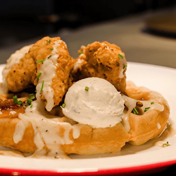 Drake's Yoke's chicken and waffles, topped with gravy, a scoop of butter, and chives.