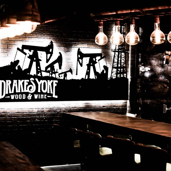 Drake's Yoke restaurant interior with a backlit logo of oil derricks and Edison bulb lighting.