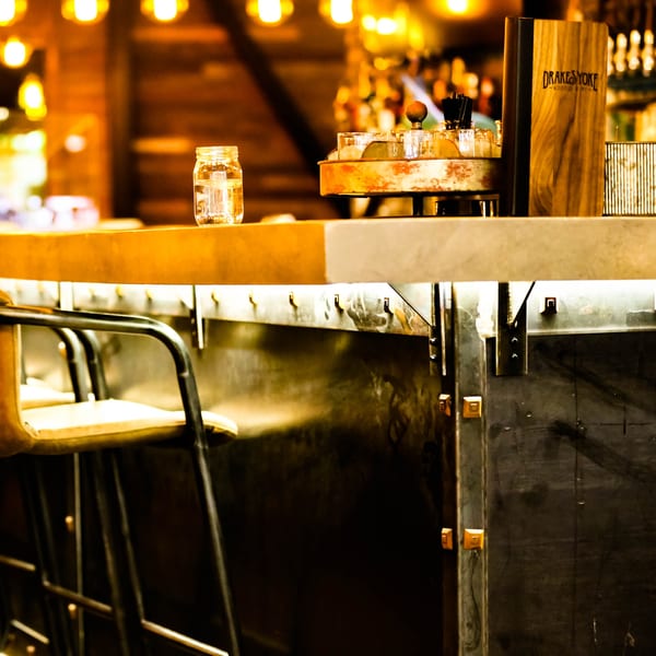 Drake's Yoke bar with a menu, mason jar, and bar stools under warm lighting.