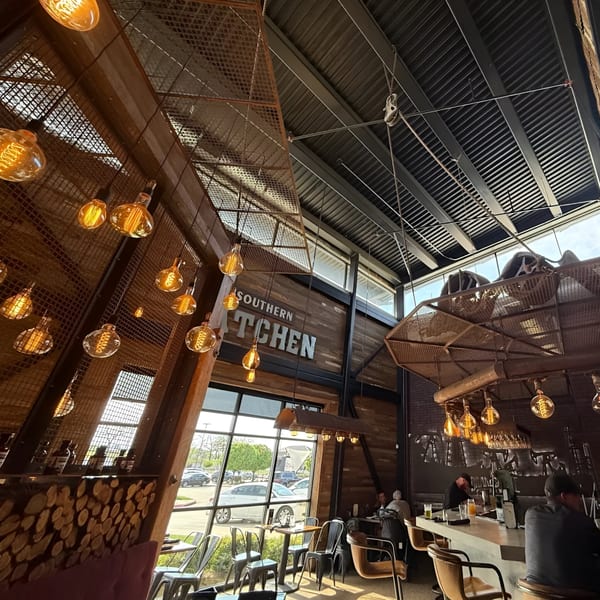 Drake's Yoke interior with high ceilings, exposed beams, industrial lighting, and a "Southern Kitchen" sign.