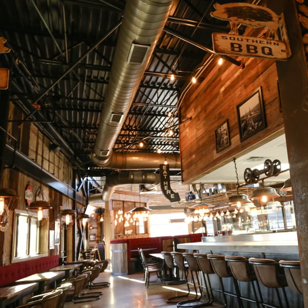 Drake's Yoke BBQ restaurant interior with rustic wood walls, industrial lighting, and a long bar.